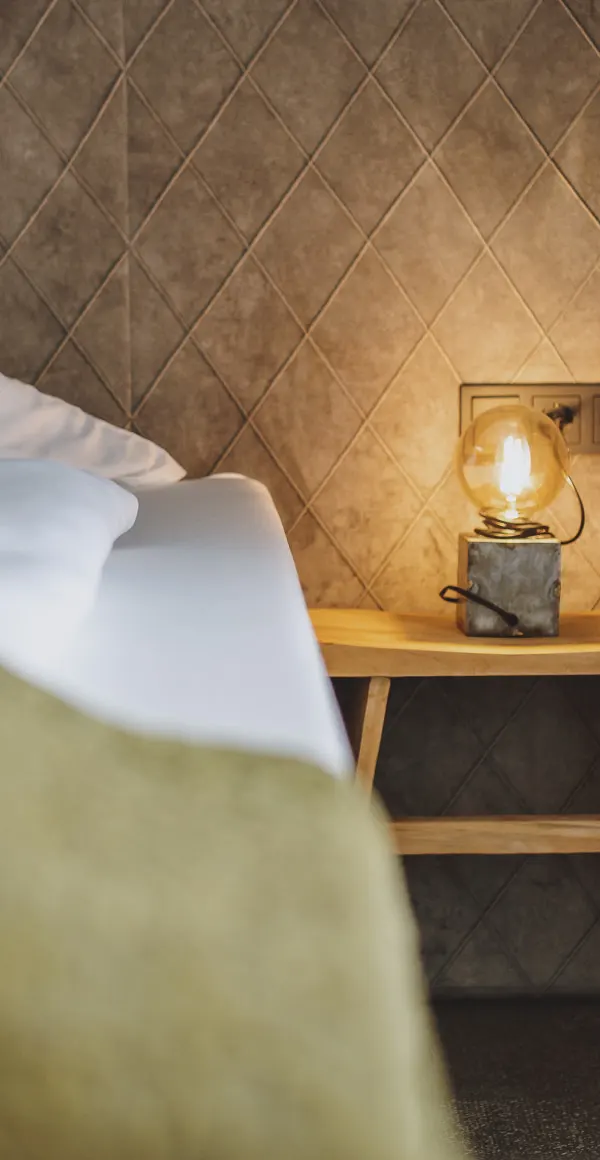 Detailansicht eines Zimmers mit Bett und Beleuchtung auf einem Tisch