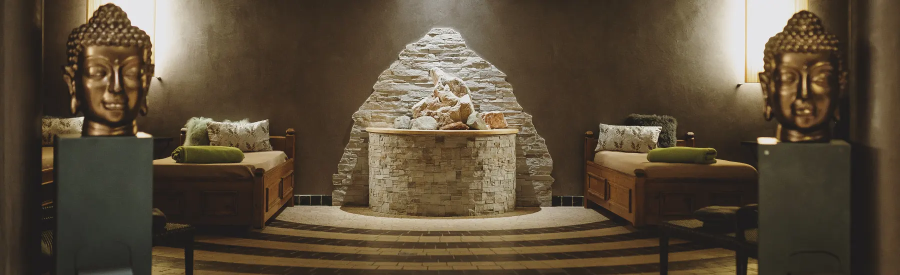 Entspannender Wellnessbereich mit Buddha-Statuen und Kamin.