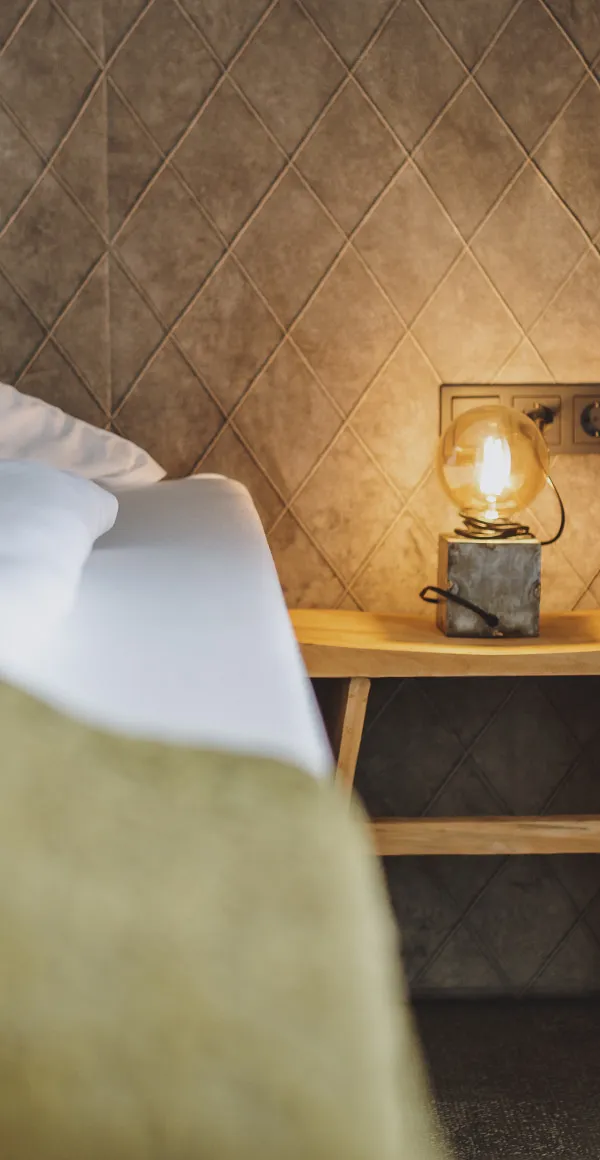 Detailansicht eines Zimmers mit Bett und dekorativer Lampe