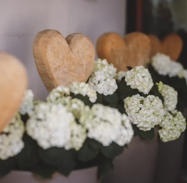 Holzherzen und weiße Blumen in einer Dekoration.