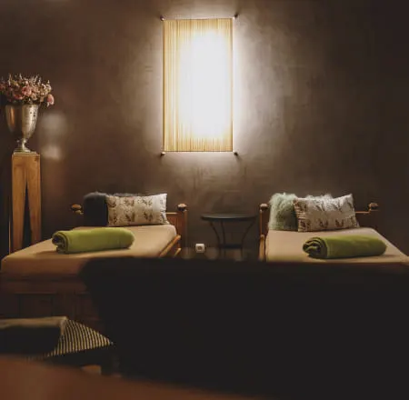 Two beds with green towels and lamp in a cozy room