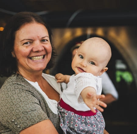 Lächelnde Frau hält ein Baby in einer Innenumgebung.