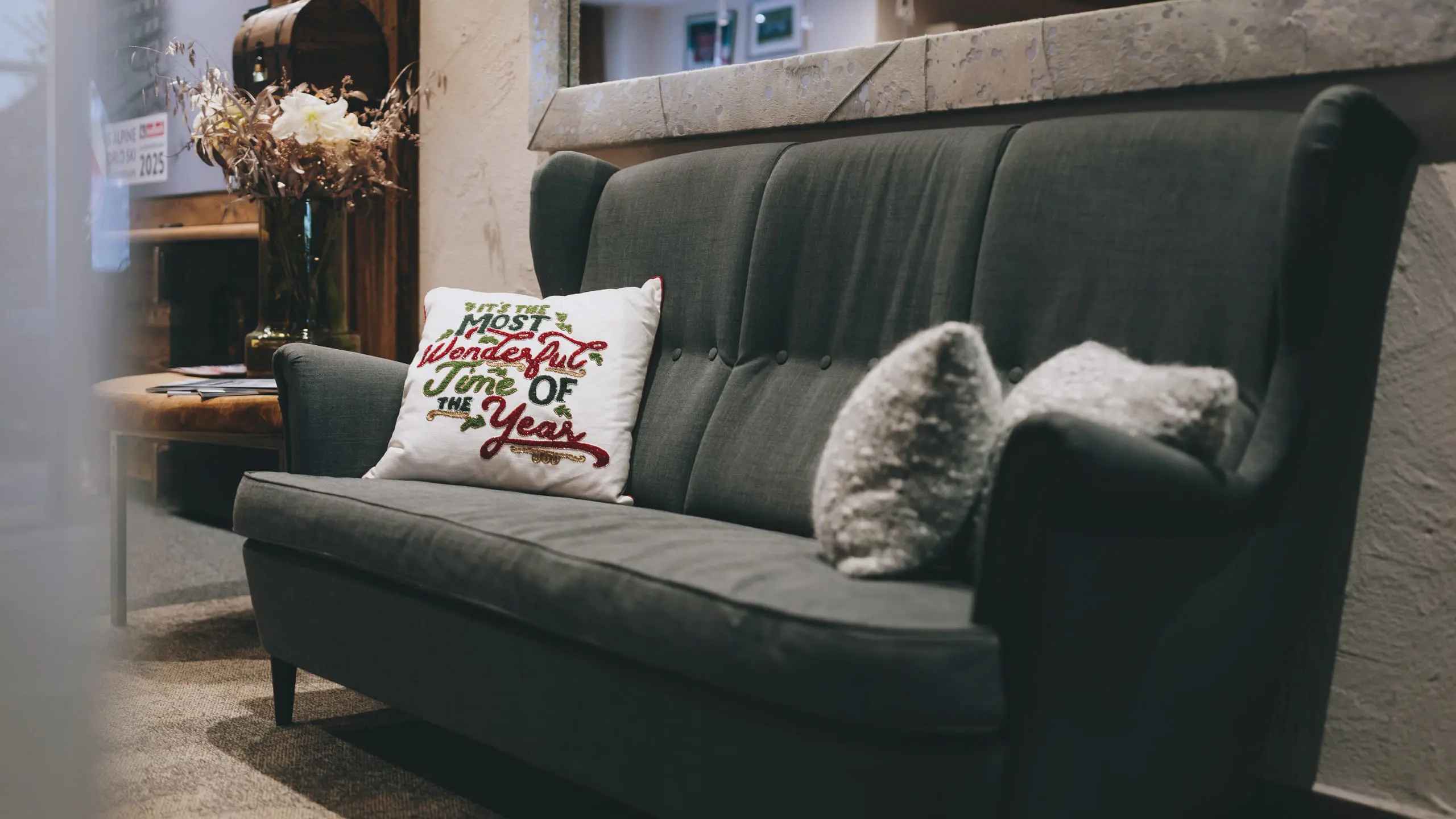 Gray sofa with cushion 'Most wonderful time of the year' and decor in the background