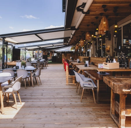 Innenansicht der Terrasse von Der Gollinger, Tische und Stühle auf Holzfußboden