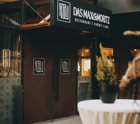 Eingang des Restaurants Max Moritz mit Pflanzen und Tischen
