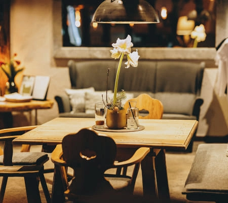 Gemütlicher Barbereich mit Holzstühlen, Tisch und Blumendeko.