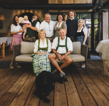 Familie posiert in traditioneller Kleidung in einem gemütlichen Raum.