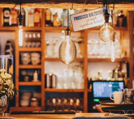 Gemütliche Bar mit Prosecco-Schild und warmem Licht.