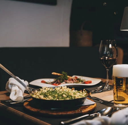 Tisch mit einem Gericht, Salat, Rotwein und Bier in einem Restaurant