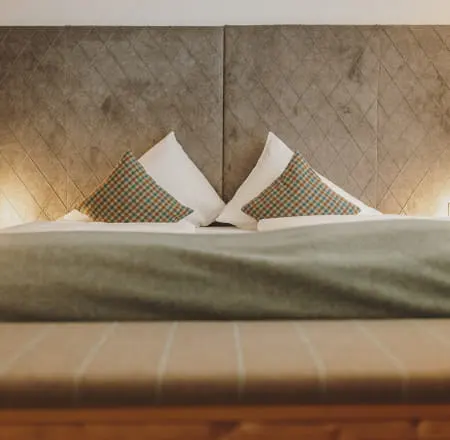 Bed with cushions and gray throw in a modern room.