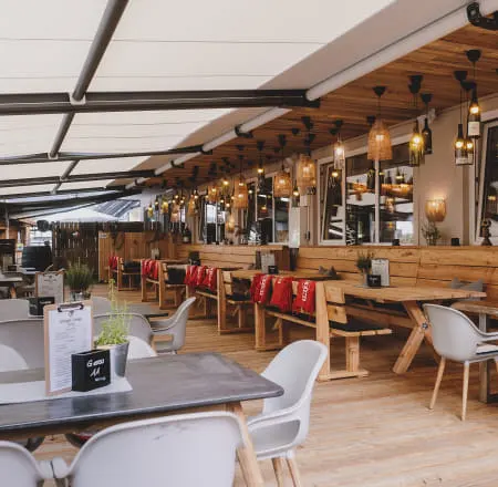 Lounge area with wooden benches, hanging lights, and tables