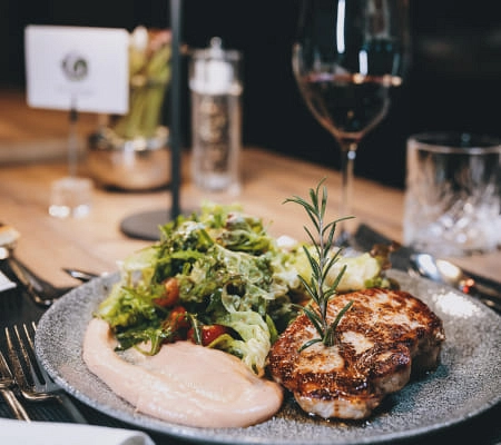 Teller mit gegrilltem Fleisch, Salat und einer Sauce in Restaurantumgebung