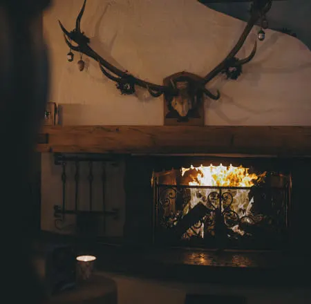 Kamin mit Holzfeuer und Geweih über dem Holzregal