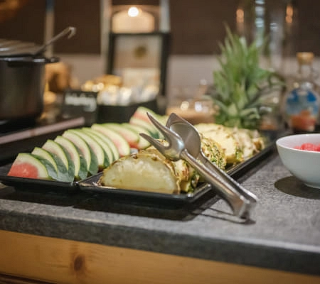 Ein Teller mit geschnittenem Wassermelone, Ananas und einer Schüssel roter Früchte.