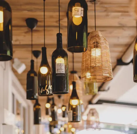 Hängende Lichtinstallationen aus Weinflaschen und einer Laterne