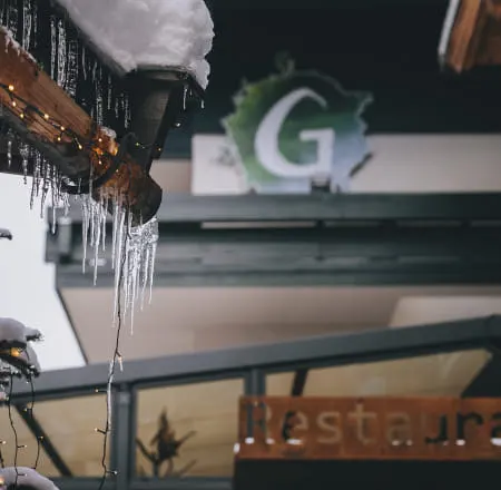 Eiszapfen hängen von einem Dach, mit einer Beschilderung im Hintergrund.