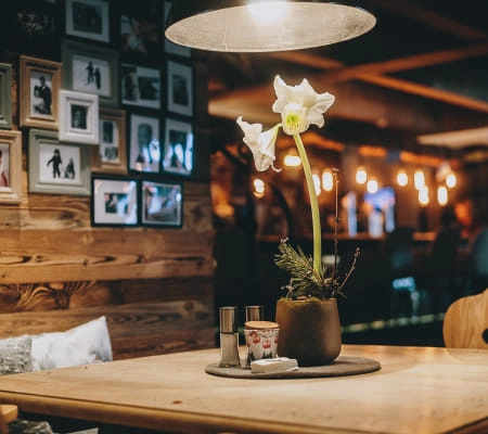 Barbereich mit Holzdetails, Fotos an der Wand und einer Amaryllisblüte auf dem Tisch.