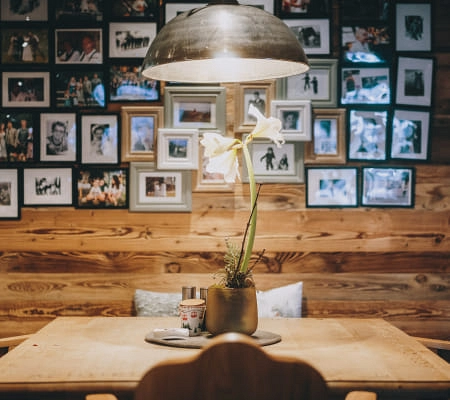 Holztisch mit Lampe und Blume, Fotowand im Hintergrund