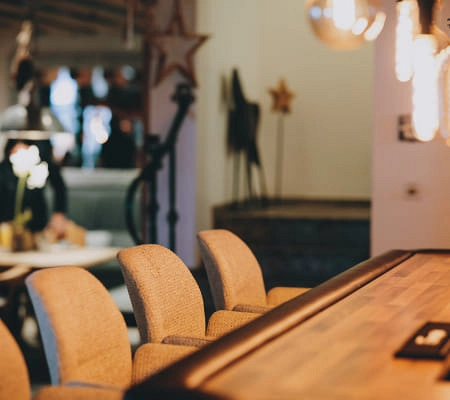 Gemütliche Bar mit Holztheke und Stühlen, Weihnachtsdekoration im Hintergrund.