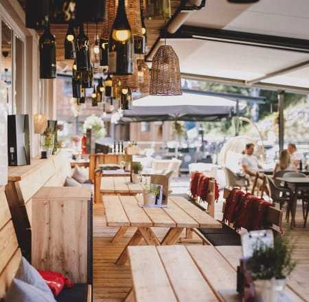 Moderne Lounge mit Holzmöbeln, Terrassenstühlen und Hängeleuchten.