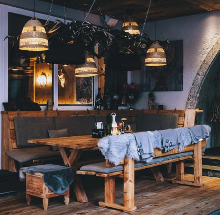 Gemütlicher Essbereich mit Holztischen und speziellen Beleuchtungselementen.