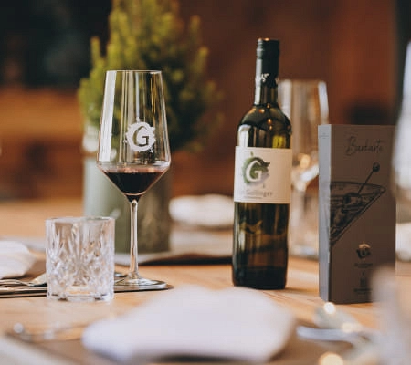 Weinglas und Flasche auf einem Tisch im Restaurant Gollinger.