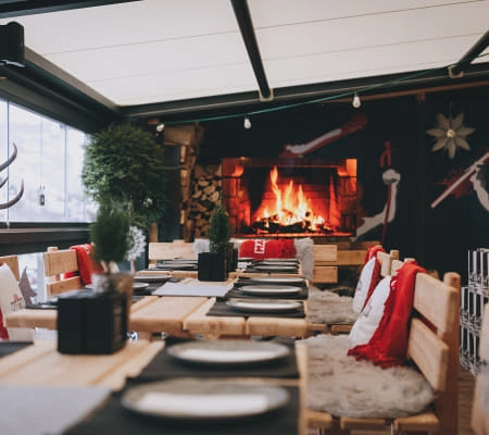 Cozy restaurant with wooden tables, rugs, and a fireplace.