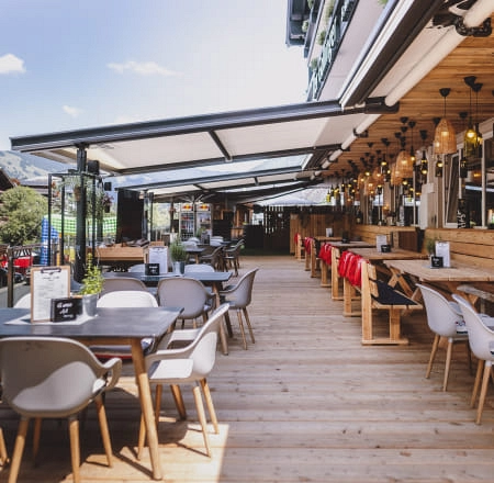 Terrasse mit Holzmöbeln und Sonnenschirmen, Blick auf die Umgebung