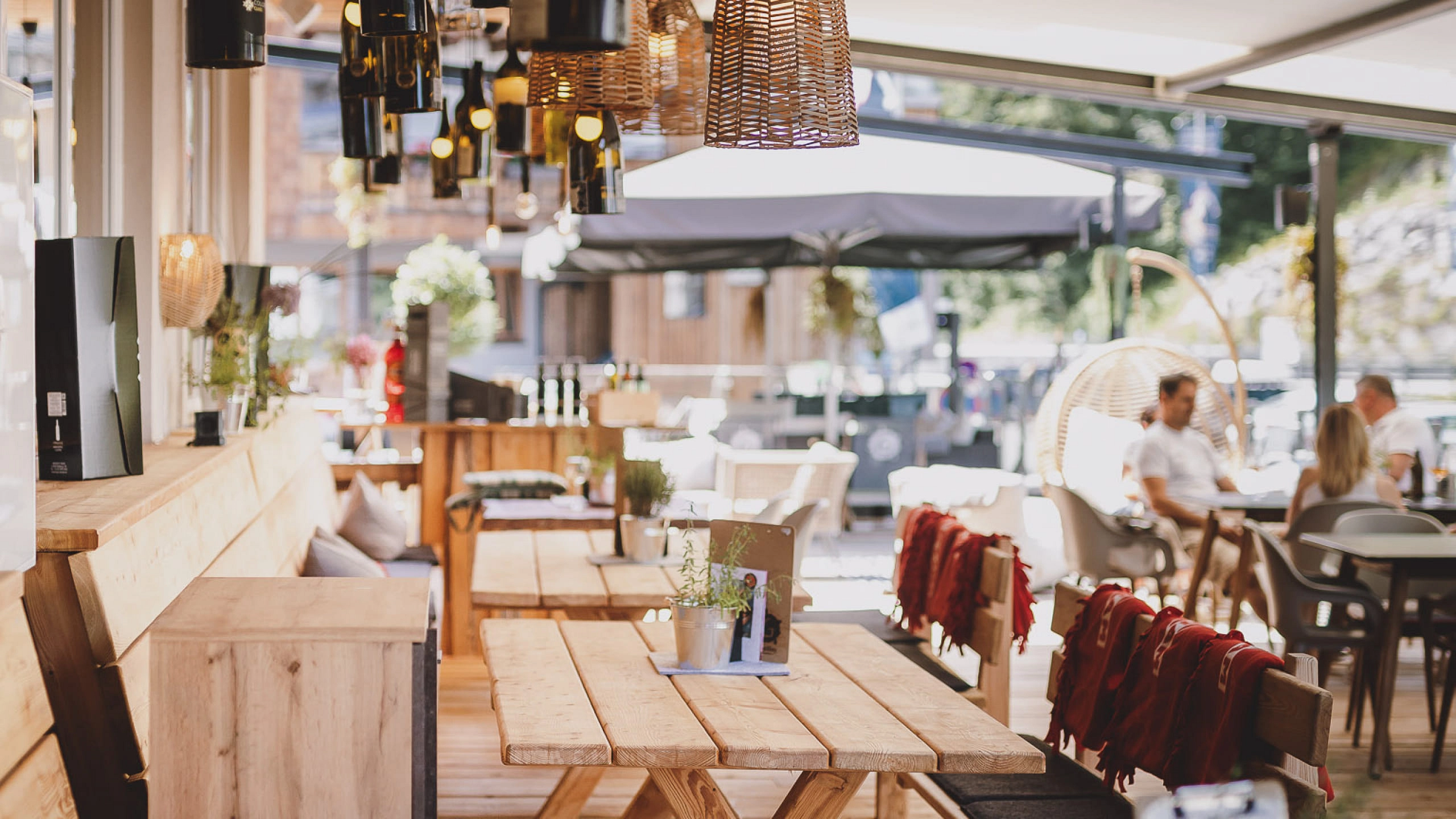 Outdoor seating area with wooden tables and hanging lamps