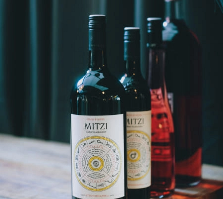 Dekorative Weinflaschen mit dem Etikett 'MITZI' auf einem Holztisch