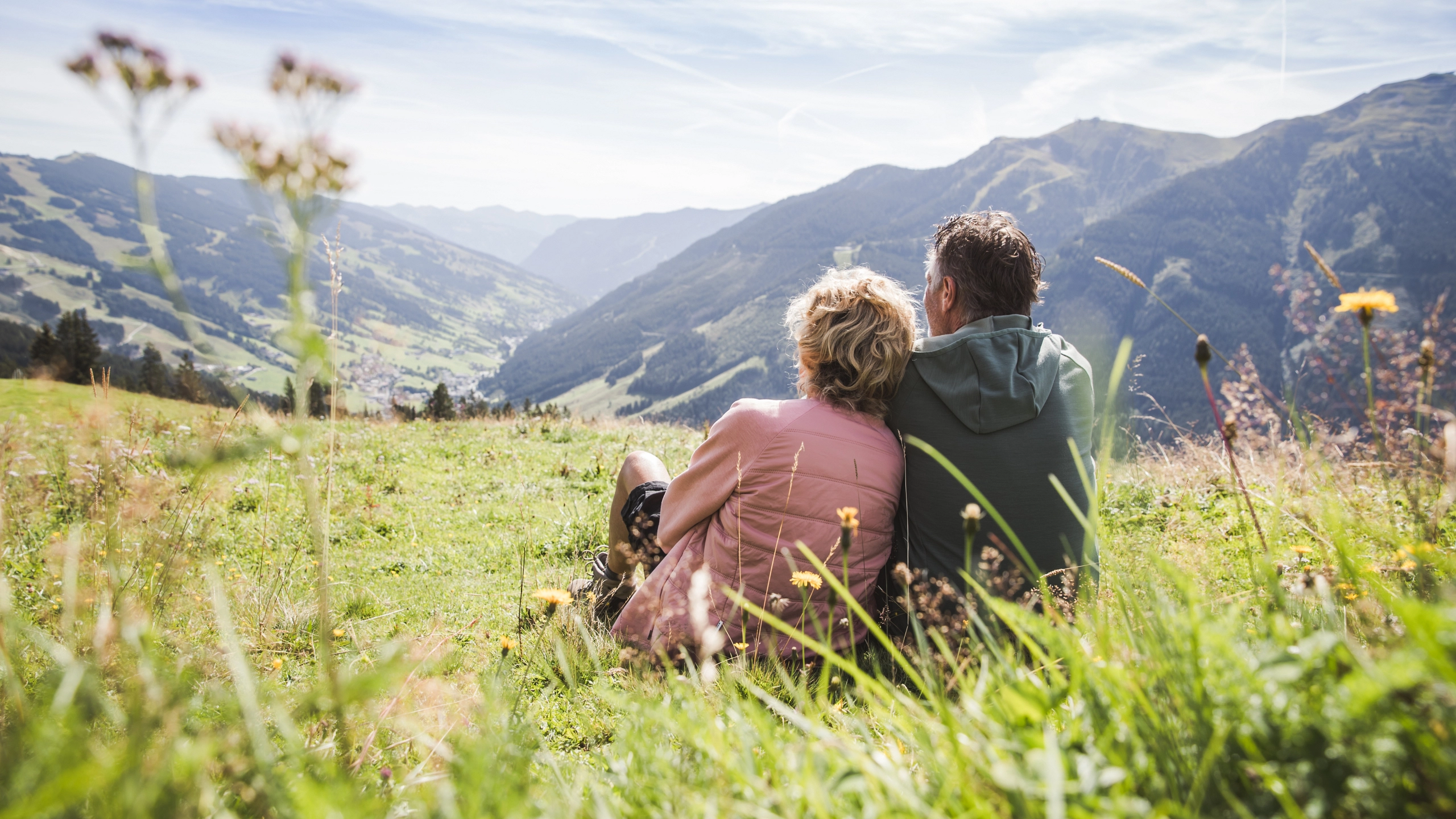 Paar sitzt auf einer Wiese in den Bergen von Saalbach Hinterglemm