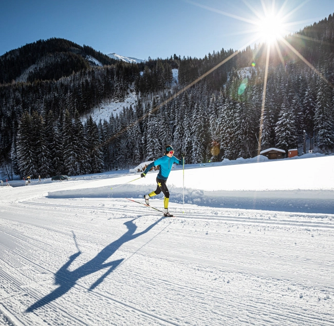 Cross-country skier on snowy track with mountains in background