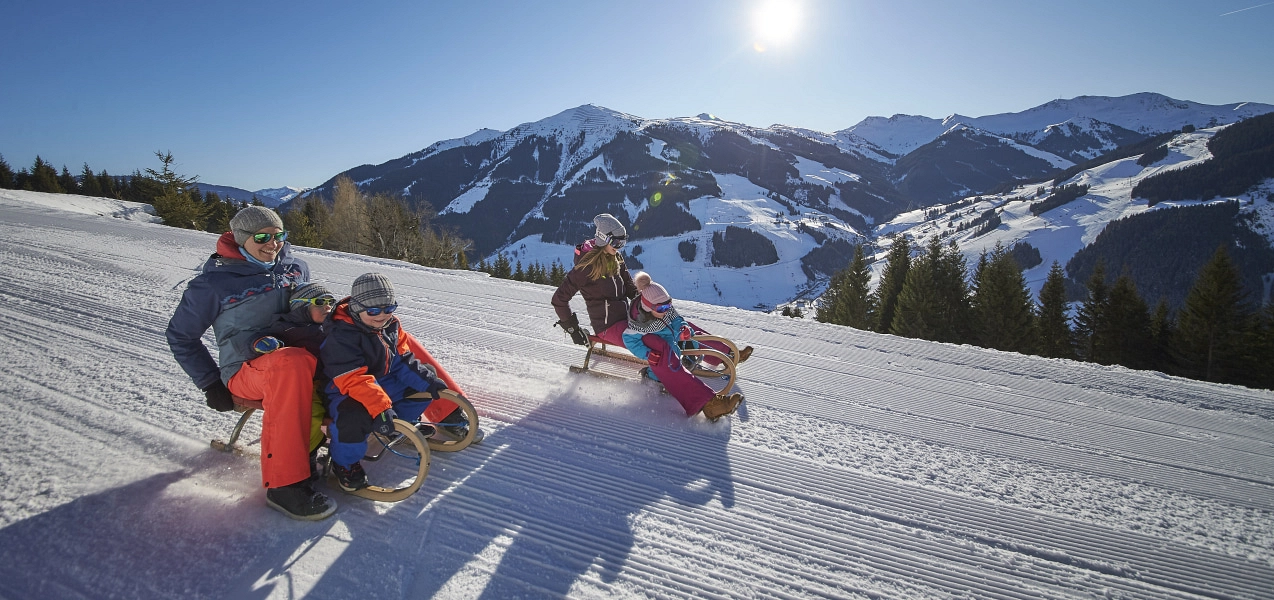 Group of people tobogganing on a snowy slope.