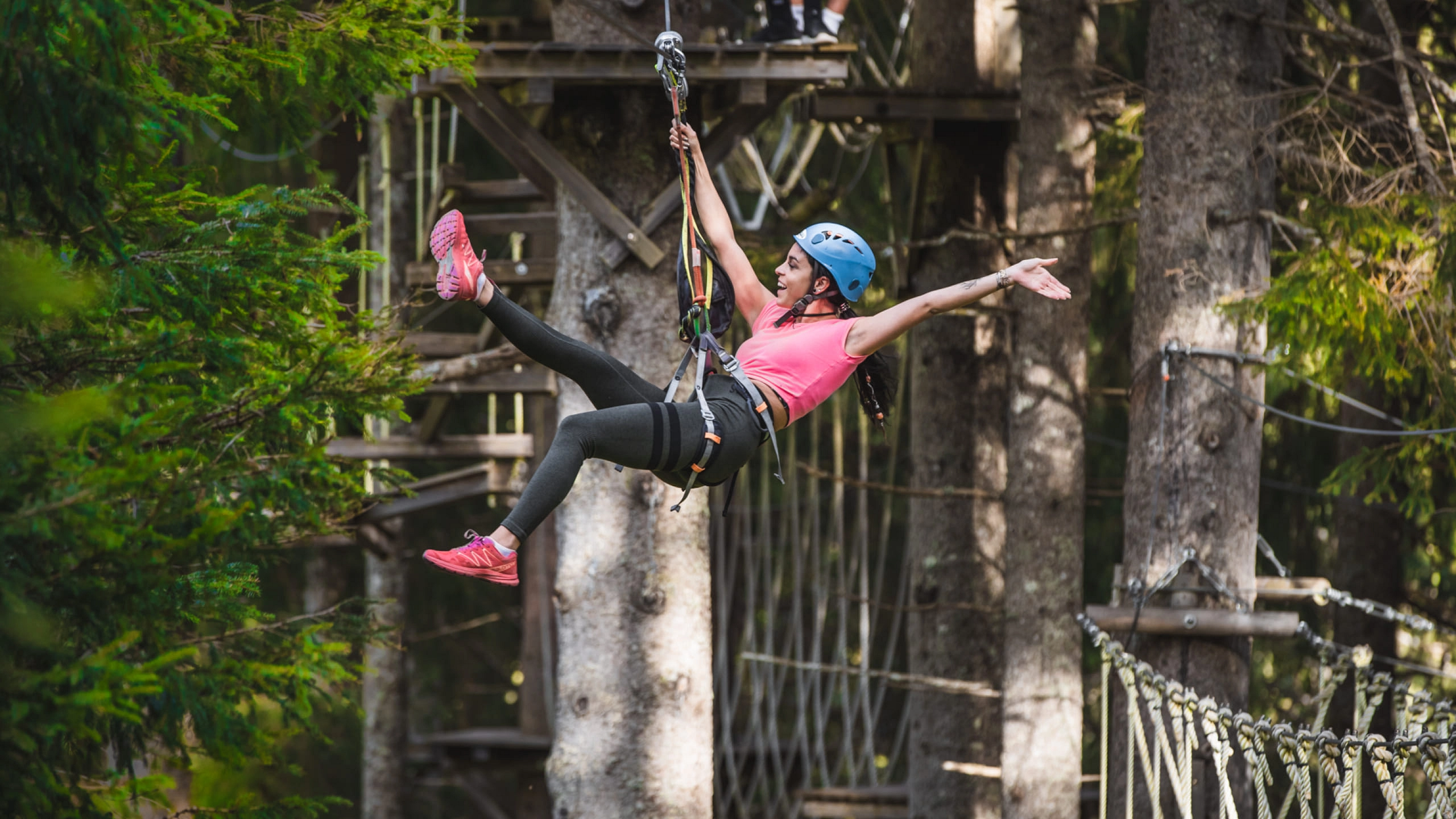 Woman swinging on a rope in a high rope course among trees