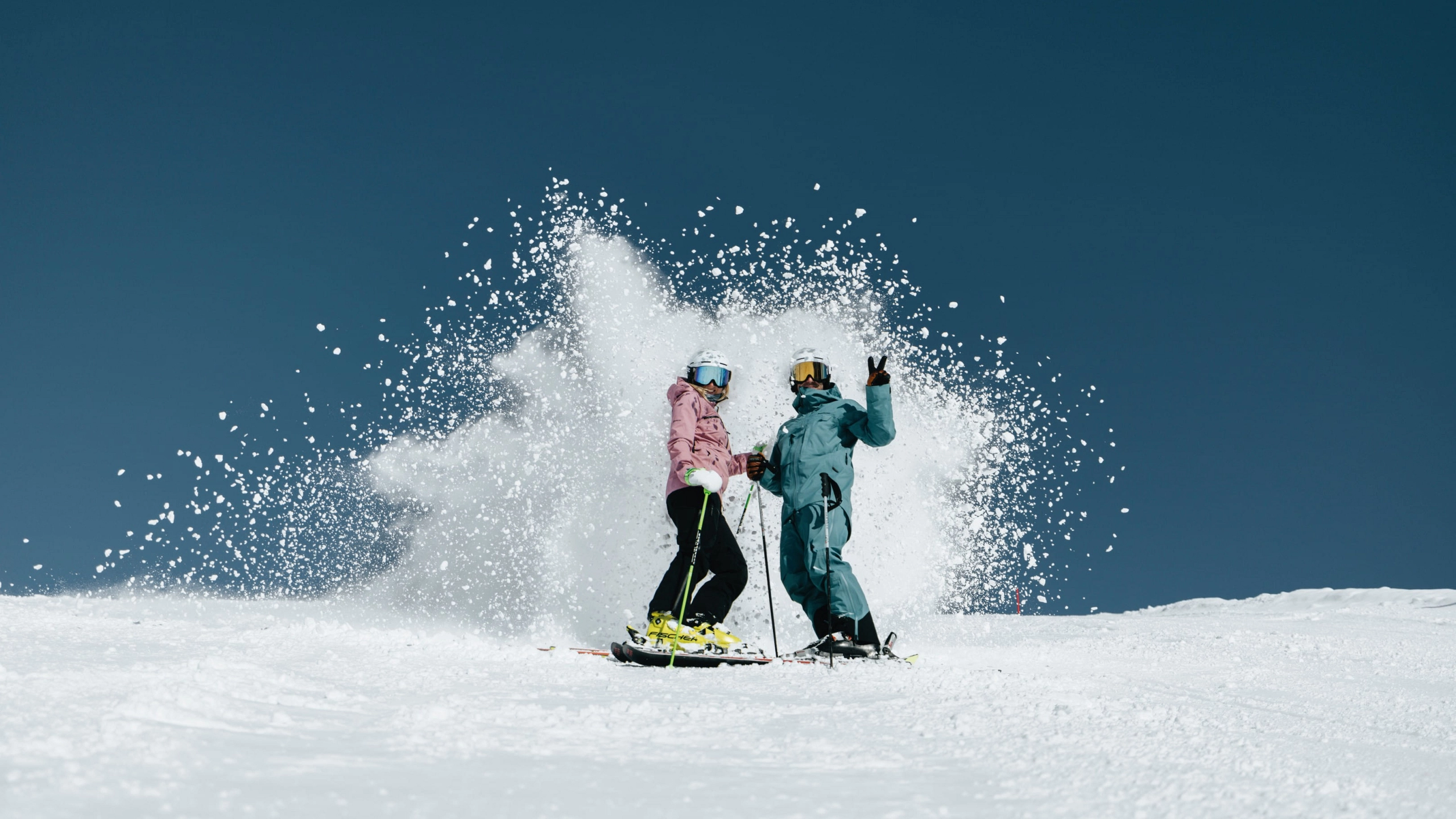 Two skiers in Skicircus Saalbach-Hinterglemm, snow spraying up.