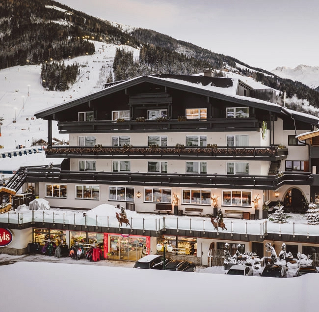 Aussenansicht eines Gebäudes mit Balkon und Sportgeschäften im Schnee