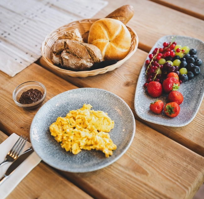 Breakfast table with scrambled eggs, bread, and fruit