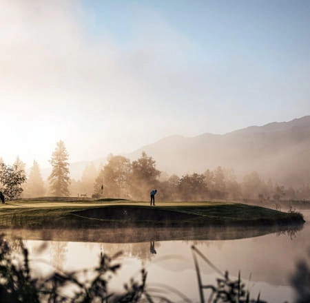 Golfspieler auf dem Platz in Zell am See, umgeben von Nebel und Bergen
