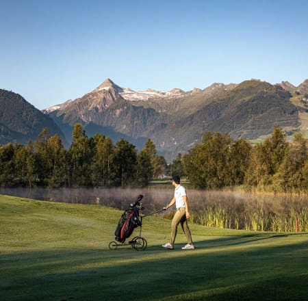 Golfende Person in Zell am See mit Bergen im Hintergrund