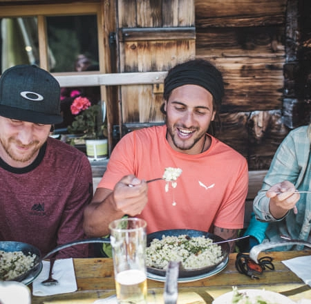 Drei Männer genießen ihr Essen in Saalbach Hinterglemm.