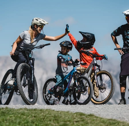 Familie mit Fahrrädern auf einem Weg in einer bergigen Landschaft
