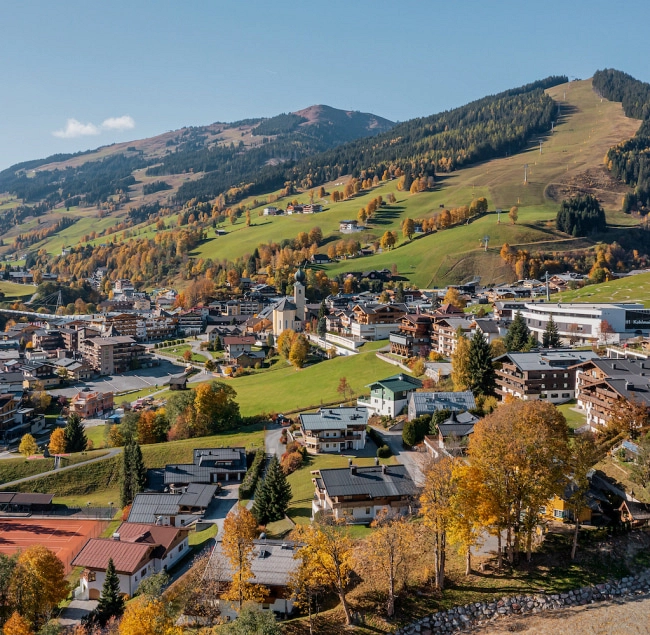 Blick auf Saalbach Hinterglemm mit herbstlichen Farben und Bergen im Hintergrund