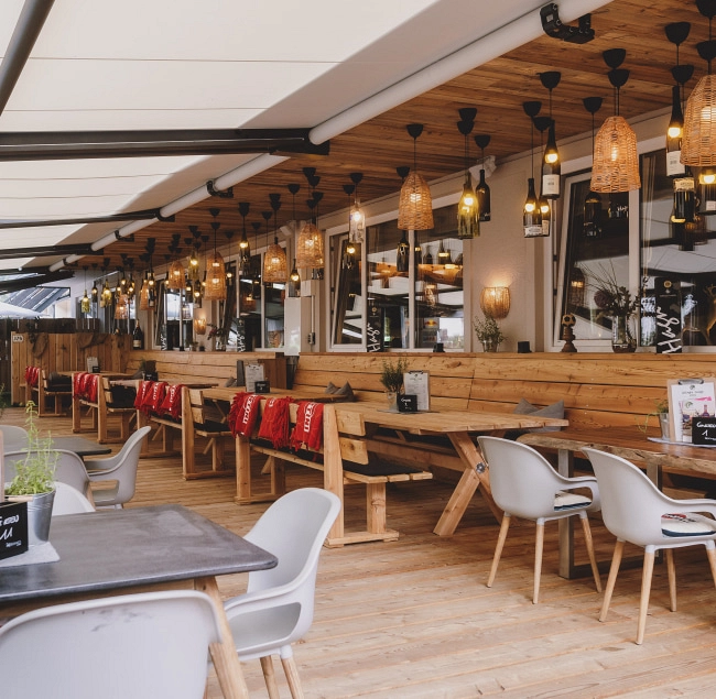 Gemütlicher Lounge-Bereich mit Holztischen und Hängeleuchten.