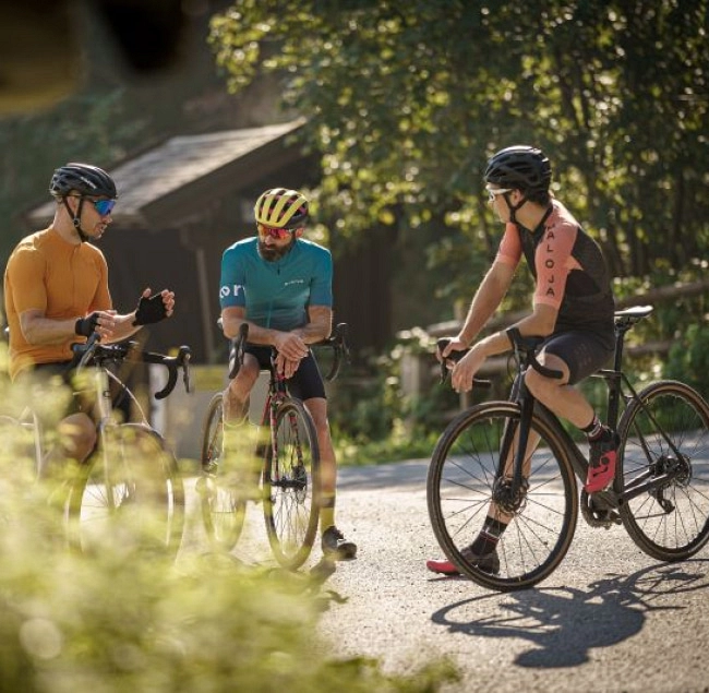 Drei Radfahrer in Saalbach-Hinterglemm unterhalten sich bei sonnigem Wetter.