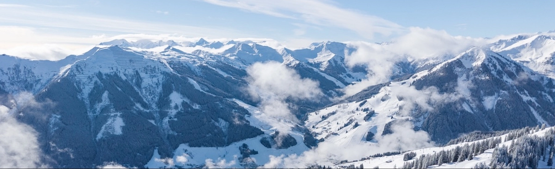 Schneebedeckte Berglandschaft mit Wolken und klarem Himmel