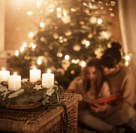 Gemütliche Szene mit Kerzen, einem Weihnachtsbaum und zwei Personen, die zusammen lesen