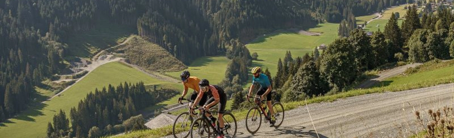 Drei Radfahrer fahren einen Schotterweg in Saalbach Hinterglemm entlang