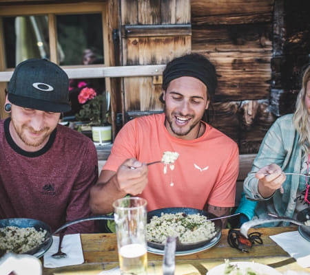 Freunde essen zusammen in einer Berghütte nach dem Wandern.