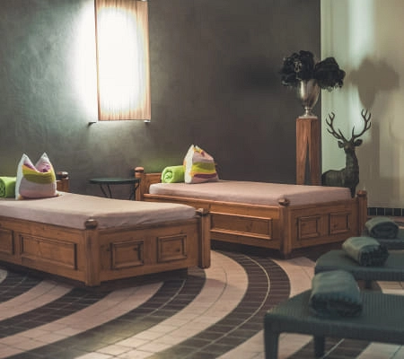 zwei hölzerne Liegebetten mit Kissen in einem Entspannungsraum