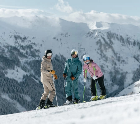 Drei Skifahrer auf einer Piste in Saalbach-Hinterglemm bei schneebedeckten Bergen